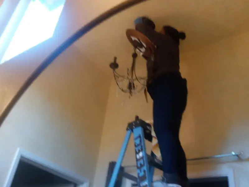 Electrician installing a chandelier in a Ellery residence